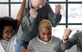 A group of employees sitting at the office table and celebrating success together